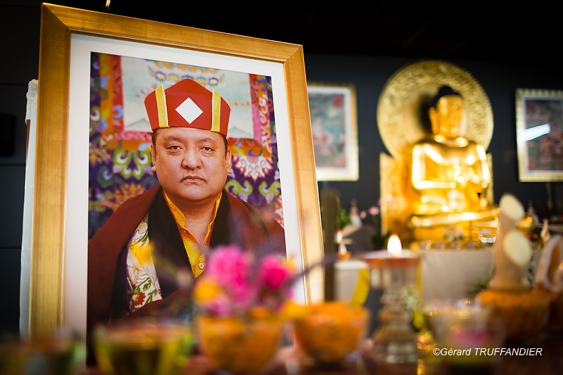 "A large photograph of Shamar Rinpoche stood on a throne before an altar set especially for him"